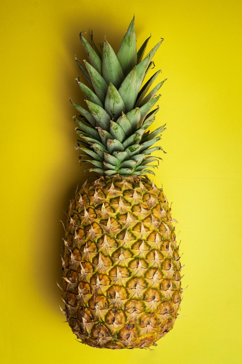 Nanas Sunpride utuh di latar kuning